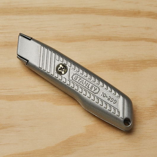 Photo of STANLEY 10-299 utility knife with metal body, angled view on wood surface.