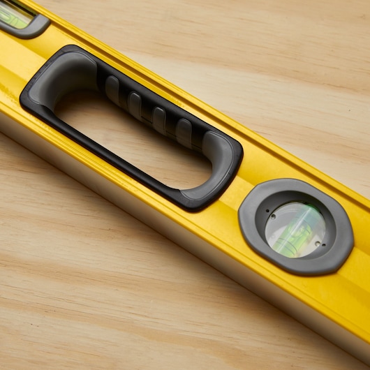 STANLEY 43-572 yellow spirit level with black handle and visible vial on wooden surface, close-up.