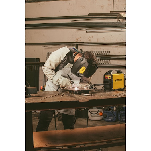 STANLEY 90369STA welder in use, worker wearing protective gear welding metal at workshop table, front angle.