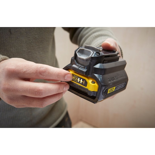 Photo of STANLEY SBA100 V20 lithium-ion battery held in hand, showing yellow label and black casing.