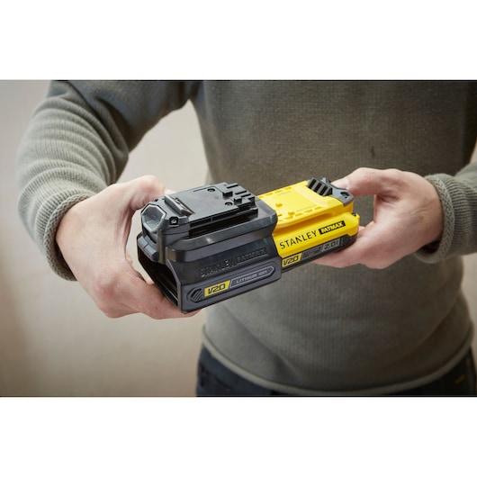 Photo of STANLEY SKU SBA100 V20 FATMAX lithium-ion batteries, person holding two units side by side.