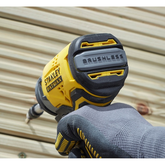Stanley SBI810D2K-B3 impact driver, yellow and black, close-up in use, gloved hand, outdoors, FATMAX branding