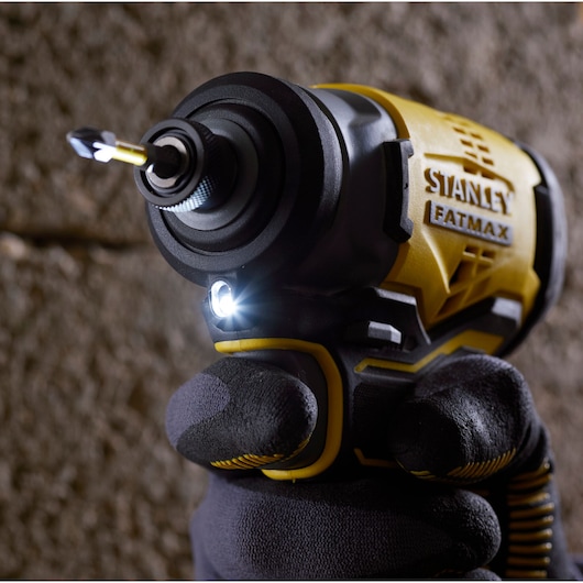 Stanley SBI810D2K-B3 impact driver close-up, yellow and black, gloved hand, LED light on, photography.