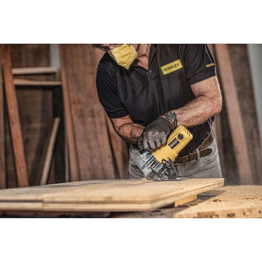 STANLEY SC16 circular saw cutting wood, photography of user wearing gloves and mask in workshop.