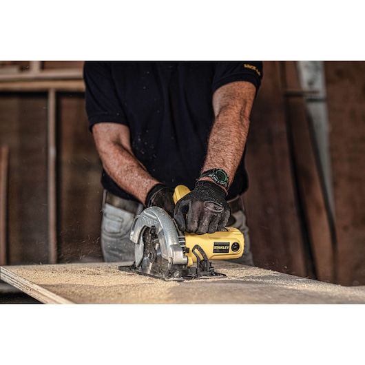 Photo of STANLEY SC16 circular saw in use, cutting wood, yellow body visible in workshop setting.