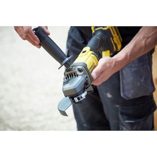 Photo of STANLEY SCG400M2K-KR yellow cordless angle grinder being assembled by hand, product close-up.
