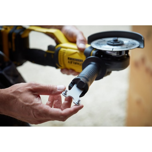 STANLEY SCG400M2K-KR angle grinder close-up, showing handle and accessory tool being held.