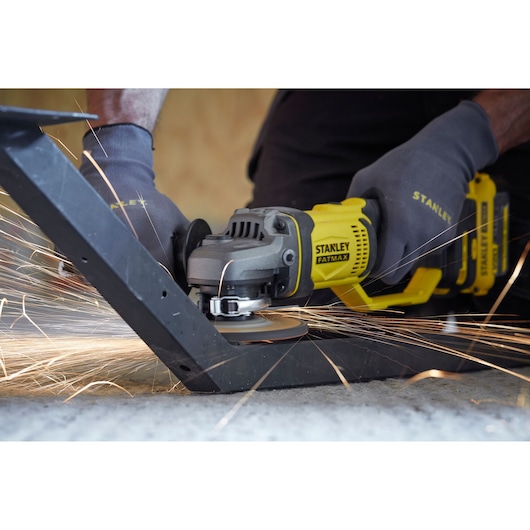 Stanley SCG400 angle grinder cutting metal with sparks, close-up photography of tool in use.