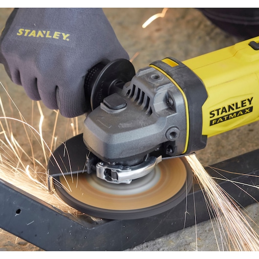STANLEY SCG400 angle grinder cutting metal with safety glove, side angle photo.
