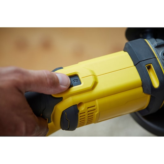 STANLEY SCG400 yellow and black grinder close-up showing power switch and hand operating it.
