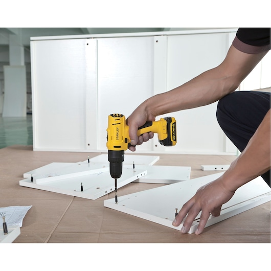 STANLEY SCH121S2K-B2 cordless drill used on white boards, side angle, assembly setting.