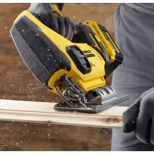 STANLEY SCJ600B jigsaw cutting wood, close-up view with sawdust scattering.