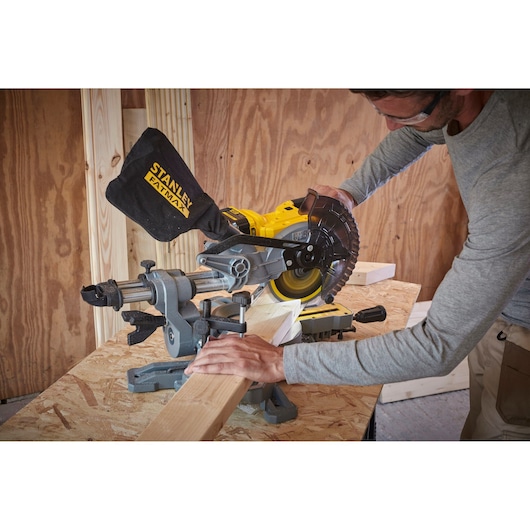 Stanley SCM701M1 miter saw in use cutting wood, shown in a workshop setting, side angle.