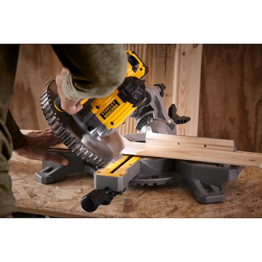 STANLEY SCM701M1 miter saw cutting wood, close-up view, yellow and silver tool on workbench.