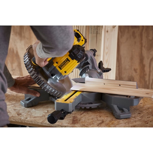 Stanley SCM701-B3 miter saw cutting wooden board, close-up angle in workshop setting.