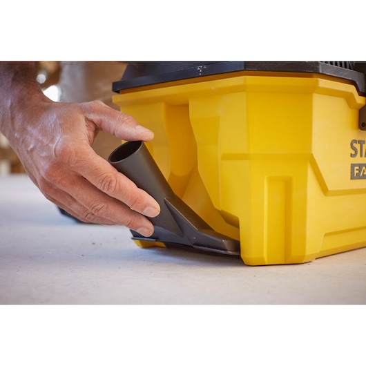 STANLEY SCV002 vacuum close-up with hand attaching black hose to yellow body, side angle.