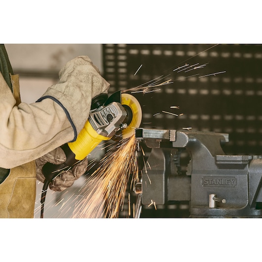 Stanley stgs9115 angle grinder in use, sparks flying as metal is cut, close-up photography.