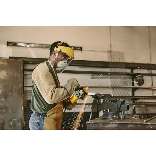 Photo of STANLEY stgs9115 bench vise in workshop, metal workpiece held and sparks flying from grinding tool.