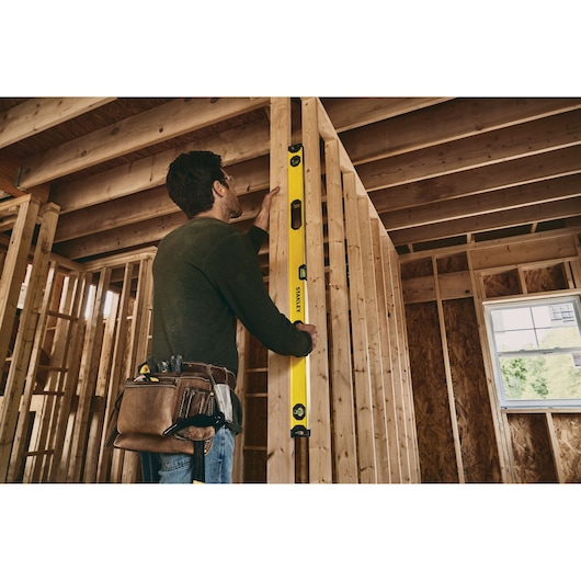 Stanley STHT42504 level tool used on wooden framing during construction, tool belt visible.