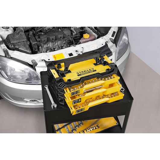 STANLEY STMT17993-LA socket and ratchet set with yellow case open on tool cart near car engine.