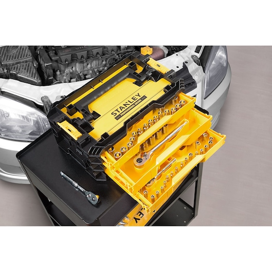 STANLEY STMT17993-LA socket set with yellow and black case, two trays extended, displayed on tool cart near car engine.