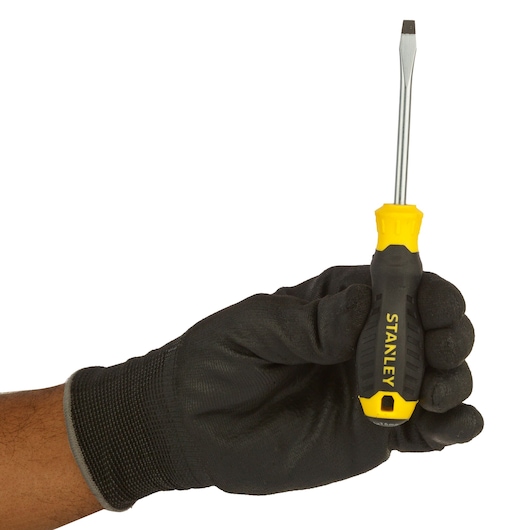 Stanley STMT60821-840 flathead screwdriver with yellow and black handle, held by gloved hand.