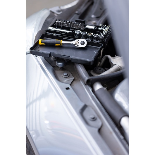 STANLEY STMT82672-0 socket and ratchet set with yellow handle, open case on a car engine bay, angled view.