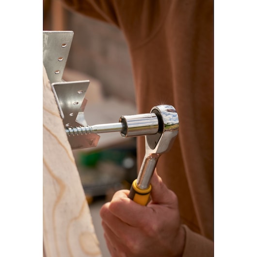 STANLEY STMT82832-1 ratchet wrench in use tightening a screw near metal bracket, close-up view.