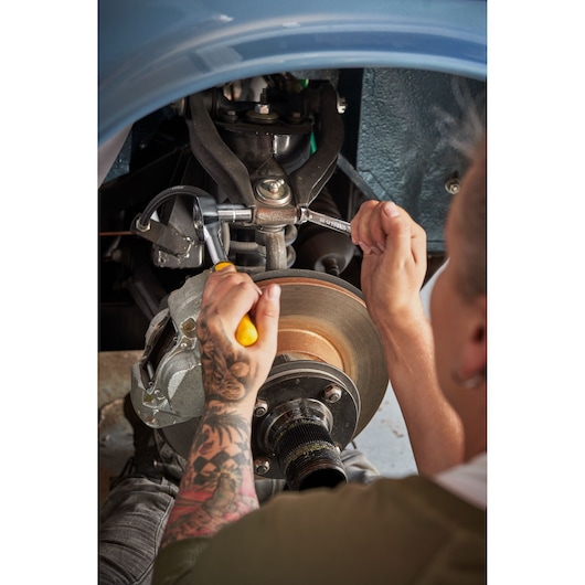 STANLEY STMT82832-LA wrench used to tighten a bolt on a car's suspension system, close-up photography.