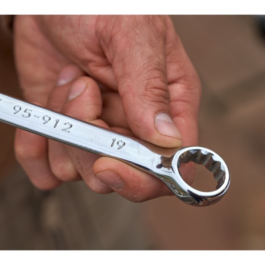 Photo of a hand holding a STANLEY STMT82832-LA chrome combination wrench, with 19 mm size marking visible.
