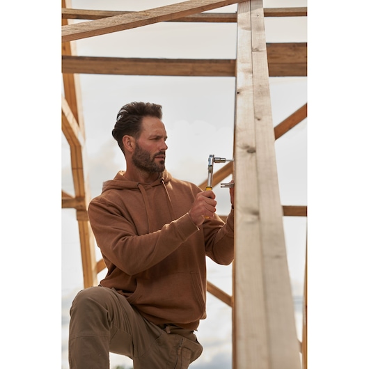 STANLEY STMT82832-LA ratchet wrench in use, person wearing brown hoodie working on wooden frame outdoors.
