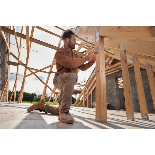 STANLEY STMT82832-LA photography of worker using hand tool on wooden frame at construction site.