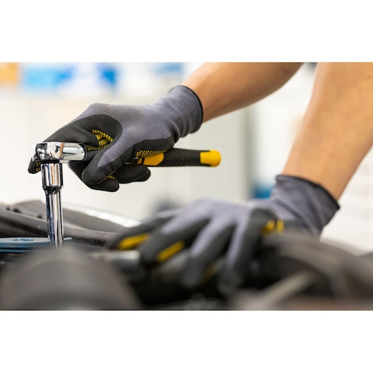 STANLEY STMT82832-LA ratchet wrench in use, close-up showing gloved hands tightening bolt on machinery.