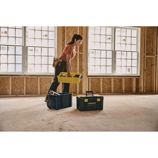 STANLEY STST18631 tool box with yellow handle shown on construction site floor, open container with tools.