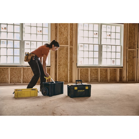 Photo of STANLEY STST18631 toolbox and two other toolboxes on a construction site floor, worker using tool belt.