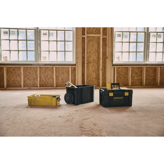 STANLEY STST18631 toolbox set with three black and yellow toolboxes, shown on a construction site floor.