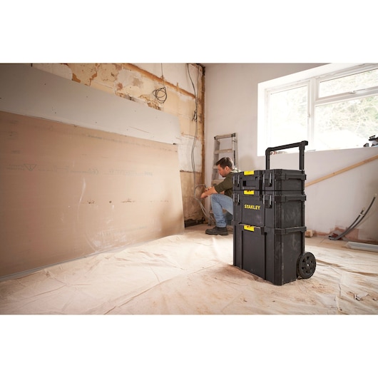 STANLEY STST83319-1 rolling tool chest in a remodel room, black plastic with yellow accents.