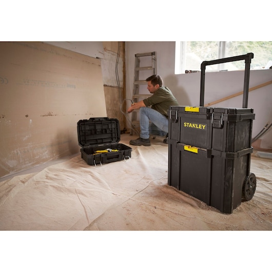 STANLEY STST83319-1 rolling tool chest shown in a workshop with open tool box in background.