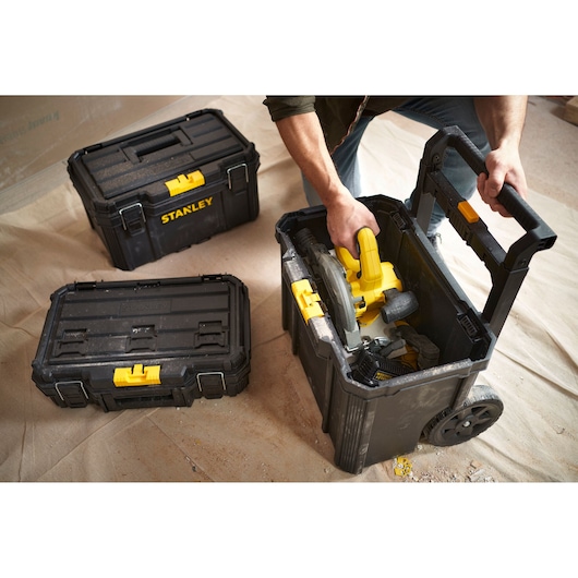 STANLEY STST83319-1 black tool boxes with yellow clasps and wheels, shown in a workshop setting.