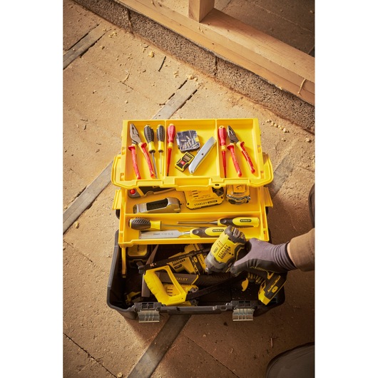 Stanley STST83397-1 toolbox with assorted hand tools, yellow tray, and power tool, top-down view.