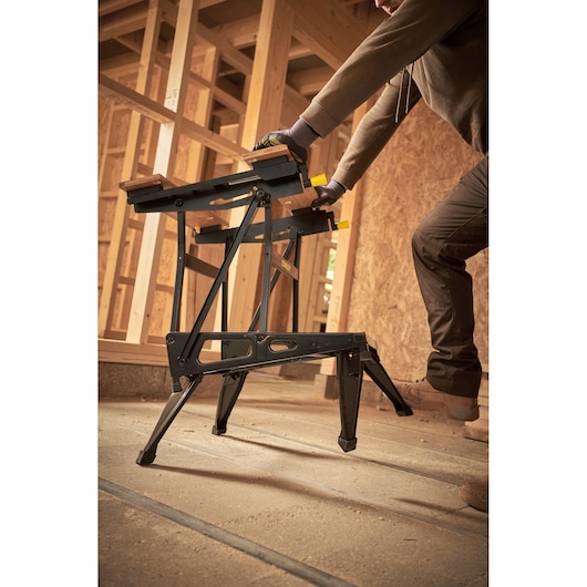 STANLEY STST83400-1 folding sawhorse in use at a construction site, black frame, wood panels on top.