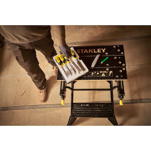 STANLEY STST83400-1 folding workbench with tools and chisels set, photographed from above in workshop setting.